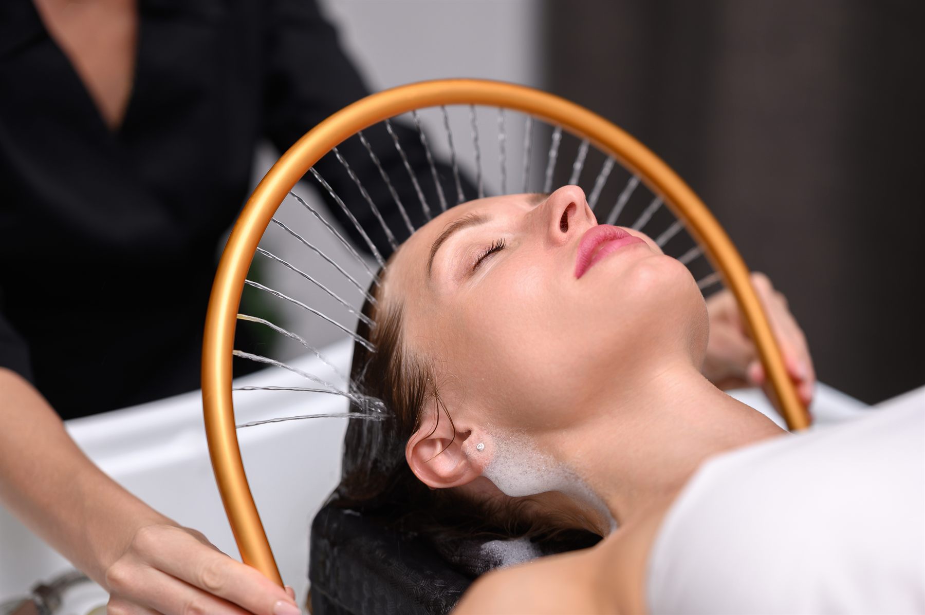 A guest receiving the Solara Head Spa Ritual beneath the overhead water wand